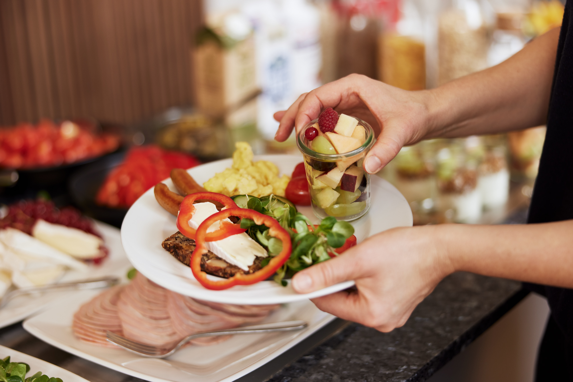En tallerken morgenmad der bliver anrettet. En ostemad med r&oslash;d peberfrugt, brunchp&oslash;lser, scrambled &aelig;g, lidt gr&oslash;nt og en et glas med sk&aring;ret frugt.
