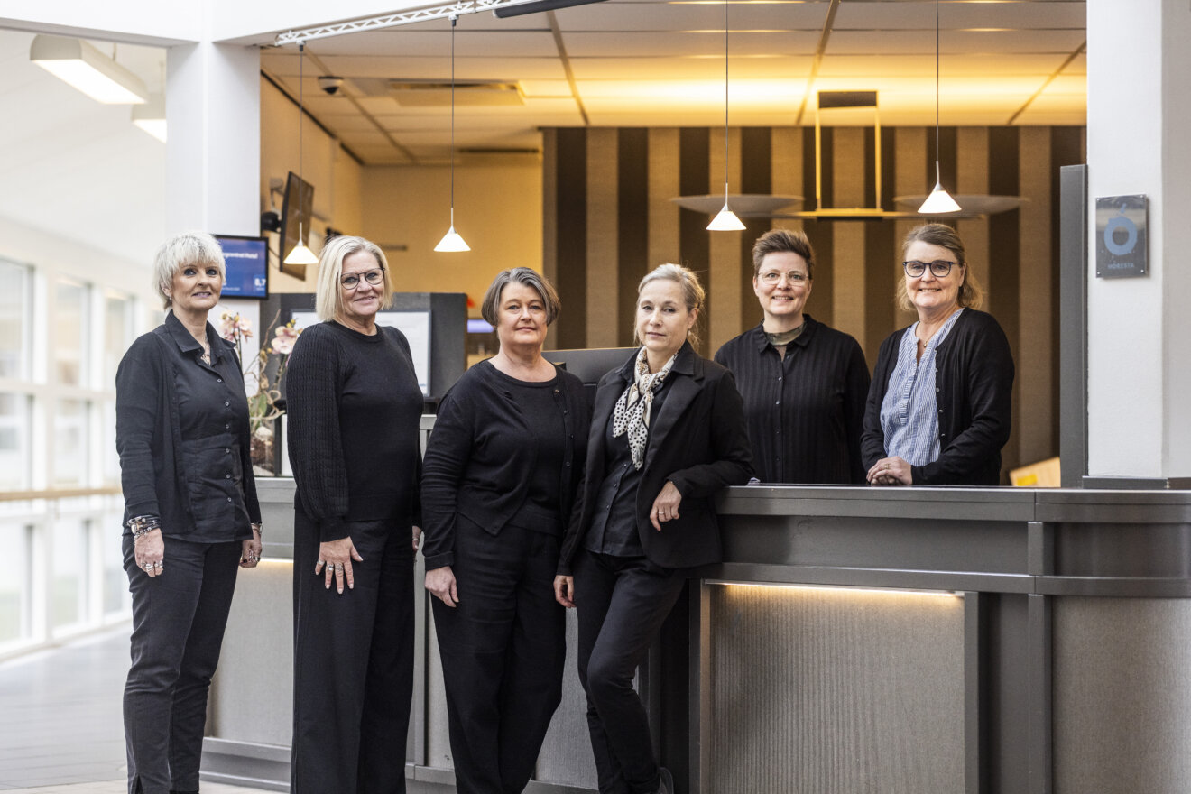Gruppebillede af medarbejderne fra receptionen - som står ved skranken. 
Fra venstre står Marianne, Heidi, Lisa, Ulla, Mette og Trine. 