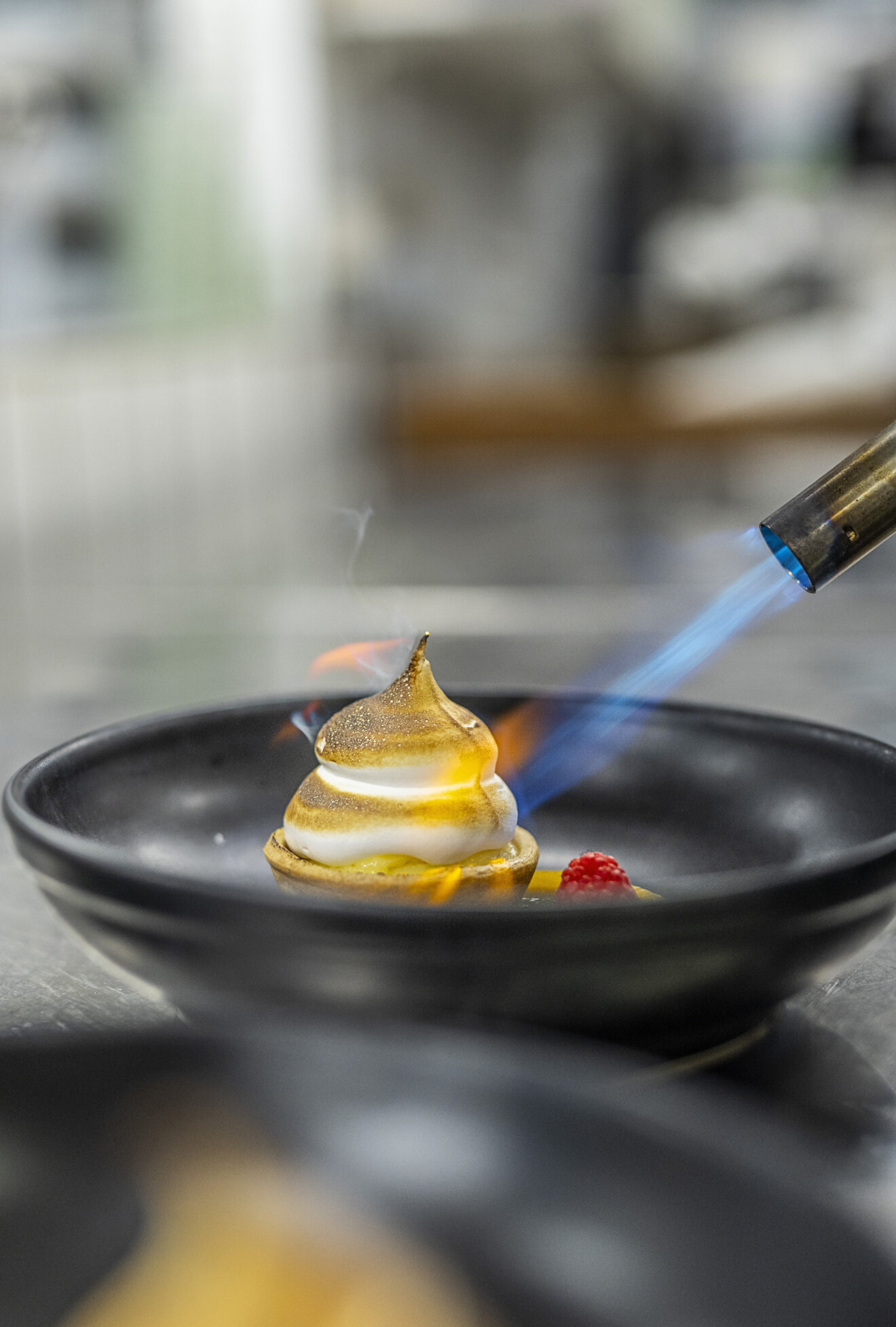 En smukt anrettet dessert er ved at blive flamberet i k&oslash;kkenet.
